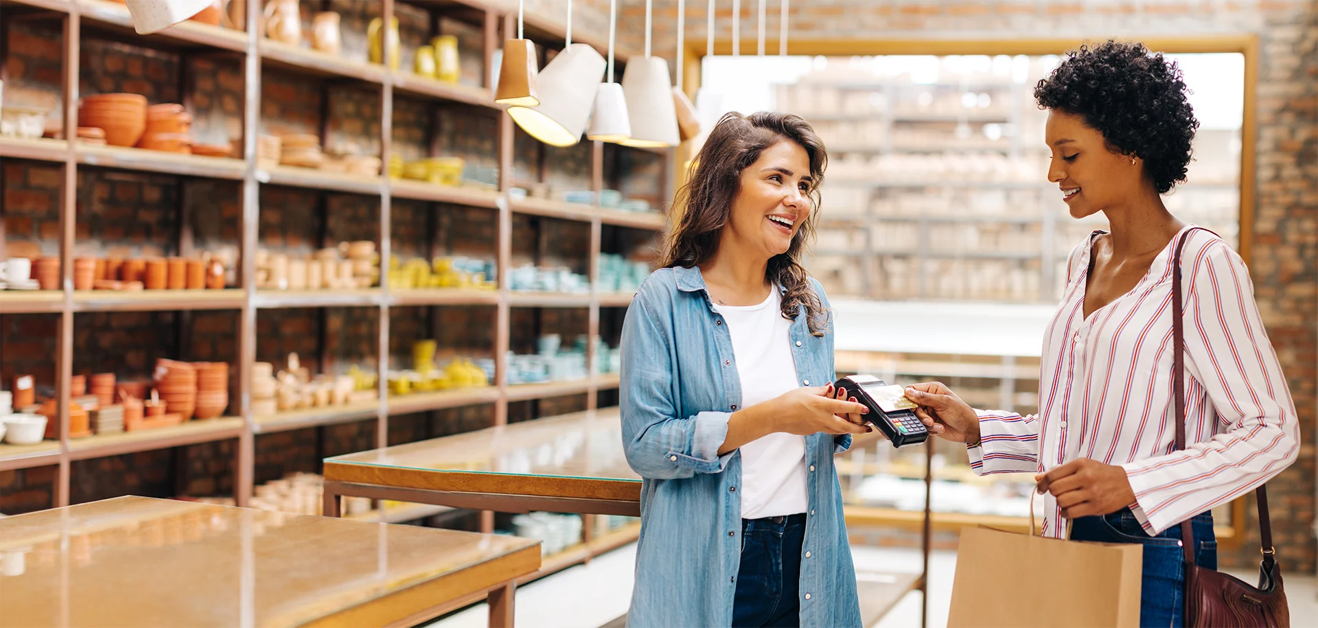 A shop employee ringing up a happy customer at the counter of an independent store